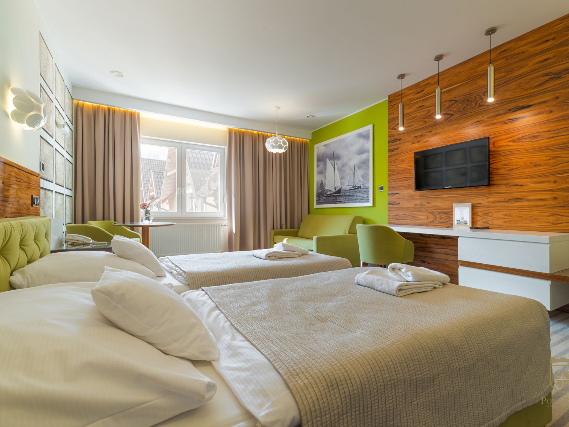 Jasny pokój hotelowy z łóżkami, fotelami i telewizorem w Hotelu Pory Roku