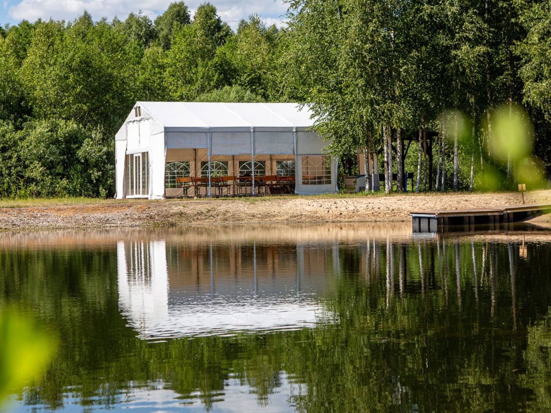 Biały namiot eventowy nad stawem przy hotelu